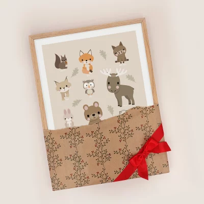 Affisch med skogsdjur i ram, inslagen i julpapper med en rosett på.