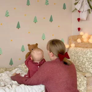 Barn som sitter i sängen och pekar på väggdekor med jul- och naturmotiv.