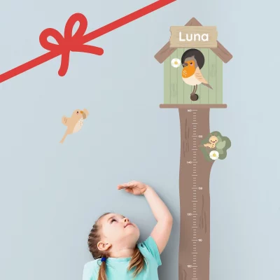 Barn som mäter sin längd vid en mätsticka formad som ett träd med fågelholk och namnet ”Luna”.