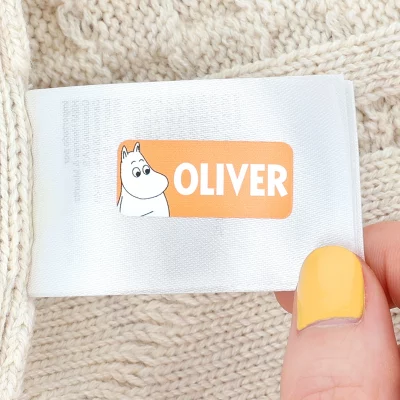 Navnelapp med navnet 'OLIVER' og illustrasjon av en Muminfigur, perfekt for å merke klær og eiendeler for barn. Ideell løsning fra vårt utvalg av personlige navnelapper.