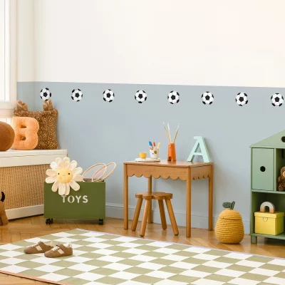 Färgglatt barnrum med väggdekor med fotbollar, ett skrivbord i trä med färgpennor och en gul leklåda. Perfekt för barn som gillar fotboll och lek.