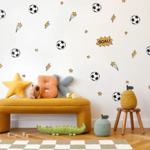 Väggdekor med fotbollstema för barnrum, inkluderar fotbollar, blixtar och stjärnor i färgglada design. En pratbubbla med texten GOAL! pryder väggen. I förgrunden syns en gul soffa med en stjärna, bokstäver i mjukt material, en leksak och korgar. Perfect för att skapa en lekfull och inspirerande miljö för barn.